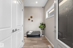 Entryway featuring light wood-finish flooring, a contemporary overhead light fixture, white trim, and a horizontal window providing natural illumination - 