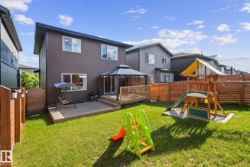 Expansive backyard featuring a manicured lawn, a raised wooden deck with a gazebo, and wooden privacy fencing - 2146 Koshal Way, Edmonton, AB 