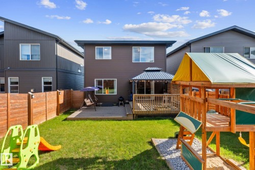 Expansive fenced backyard featuring a manicured lawn, a wooden deck, and an integrated gazebo - 2146 Koshal Way, Edmonton, AB 