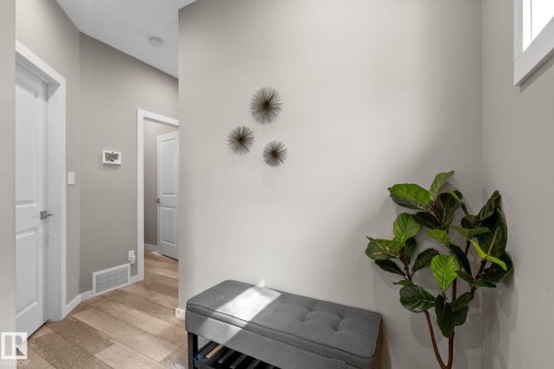 Hallway featuring wood-finish flooring, light grey painted walls, and white trim - 2146 Koshal Way, Edmonton, AB 