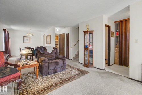 Carpeted living area with light-colored walls and a decorative area rug - 18409 66 Avenue, Edmonton, AB 