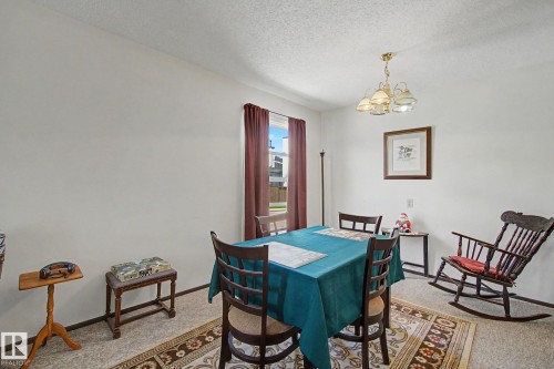 Dining area featuring a window with brown drapery, a brass-finish chandelier, and light-colored flooring - 18409 66 Avenue, Edmonton, AB 
