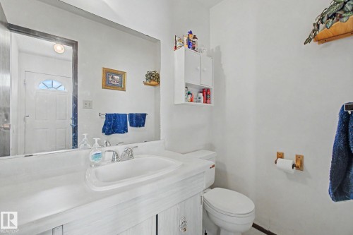 Bathroom featuring a vanity with an integrated sink, a large wall-mounted mirror, and a built-in wall cabinet for storage - 18409 66 Avenue, Edmonton, AB 