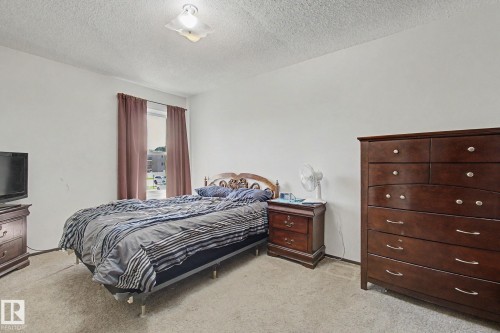Carpeted room with a window featuring brown drapes, white walls, and a flush mount ceiling light fixture - 18409 66 Avenue, Edmonton, AB 