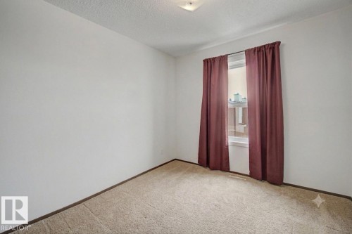 Light-filled room featuring neutral wall paint, textured ceiling, a single window, and carpet flooring - 18409 66 Avenue, Edmonton, AB 