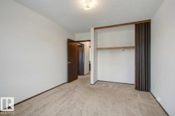 Carpeted room featuring a built-in closet with sliding dark wood doors and an integrated clothing rod - 