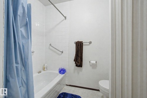 Bathtub with white subway tile surround, chrome grab bars, and a chrome shower rod - 18409 66 Avenue, Edmonton, AB 