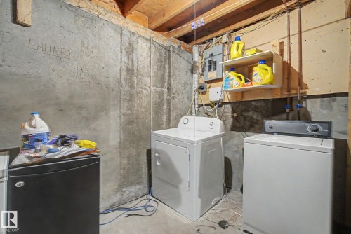 Utility area featuring a concrete floor, exposed wood ceiling joists, and a built-in wall shelf - 18409 66 Avenue, Edmonton, AB 