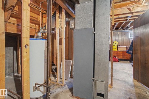 Basement utility area featuring exposed wood framing, concrete flooring, a water heater, and visible ductwork - 18409 66 Avenue, Edmonton, AB 