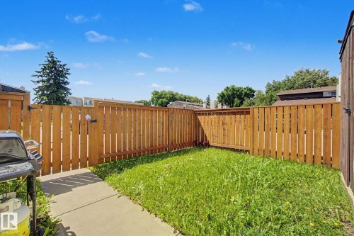 Private backyard featuring a concrete patio, a wooden privacy fence, and a grassy lawn area - 18409 66 Avenue, Edmonton, AB 