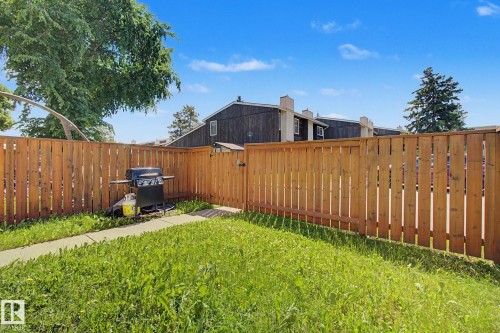Enclosed backyard featuring a wood privacy fence, a grass lawn, and a concrete pathway - 18409 66 Avenue, Edmonton, AB 
