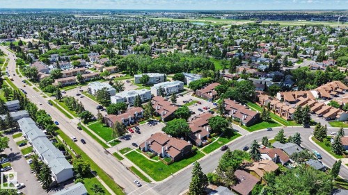 Aerial perspective showcasing a residential area with varied property types, including multi-unit buildings and single-family homes, surrounded by mature trees and paved roads - 18409 66 Avenue, Edmonton, AB 