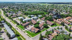Aerial perspective showcasing a residential area with varied property types, including multi-unit buildings and single-family homes, surrounded by mature trees and paved roads - 