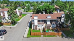 Townhome complex featuring brown siding and white accents, individual fenced yard spaces, and dedicated parking - 