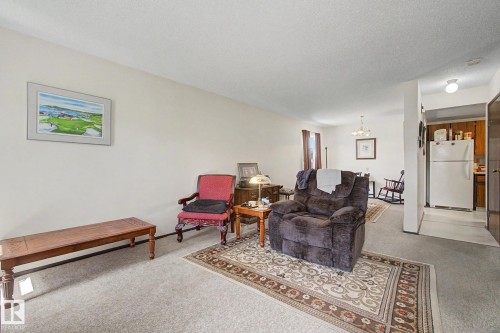 Carpeted living area with light-colored walls and a wall-mounted light fixture - 18409 66 Avenue, Edmonton, AB 
