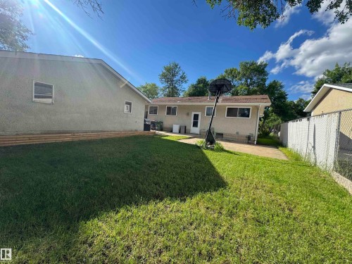 Expansive green lawn with mature trees, stucco exterior, and a chain-link fence - 45 Lambert Crescent, St. Albert, AB 