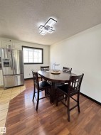 Dining area featuring wood-finish flooring and a contemporary linear ceiling light fixture - 
