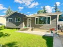 Contemporary exterior featuring dark gray siding, white trim, a wide front window, a covered entryway, and a concrete patio - 45 Lambert Crescent, St. Albert, AB 