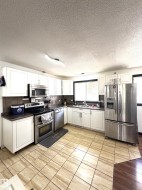 Kitchen featuring white cabinetry, stainless steel appliances, a double basin sink, tiled backsplash, and wood-finish countertops - 
