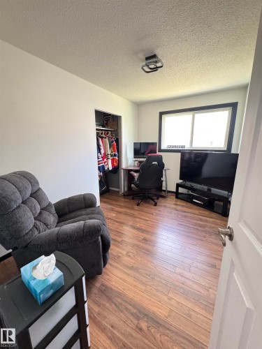 Interior room with wood-finish flooring, white painted walls, and a visible closet - 45 Lambert Crescent, St. Albert, AB 
