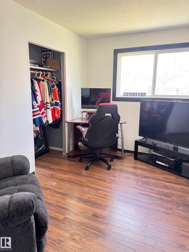 Room featuring wood-finish flooring, a window with dark trim, and a built-in closet with an interior rod - 45 Lambert Crescent, St. Albert, AB 