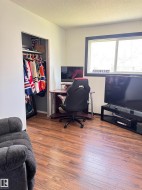 Room featuring wood-finish flooring, a window with dark trim, and a built-in closet with an interior rod - 