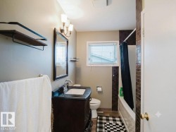 Bathroom featuring a dark wood-finish vanity with an integrated sink, rectangular mirror, and three-light vanity fixture - 