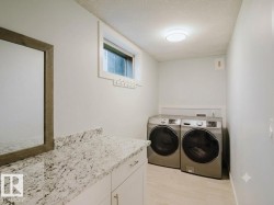 Laundry area featuring a built-in white cabinetry, light-toned countertop, a window with white trim, and light-colored flooring - 