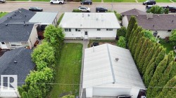 Rear yard featuring a detached garage with a white garage door, a manicured lawn, and mature privacy trees - 