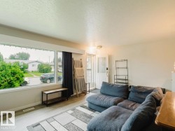 Living area featuring a large picture window, wood-finish flooring, and white painted walls - 