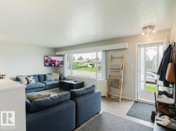 Bright living area featuring large windows, wood-finish flooring, and a contemporary ceiling light fixture - 
