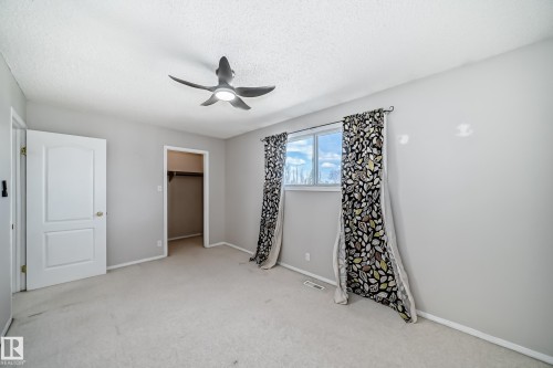 Carpeted room featuring light gray walls, a ceiling fan with integrated lighting, and a window with a white frame - 7317 83 Avenue, Edmonton, AB 