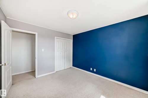 Carpeted room featuring a ceiling-mounted light fixture, a wide entry, and bi-fold closet doors - 7317 83 Avenue, Edmonton, AB 
