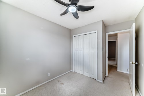 Carpeted room featuring a ceiling fan with integrated lighting, bi-fold closet doors, and neutral wall paint - 7317 83 Avenue, Edmonton, AB 