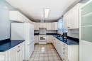 U-shaped kitchen featuring white cabinetry, blue countertops, and a white tile backsplash - 7317 83 Avenue, Edmonton, AB 