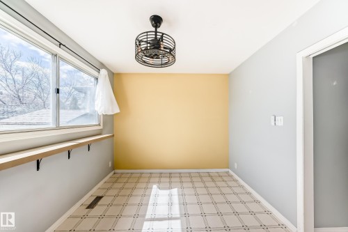 Bright room featuring a large window, patterned floor, and a black cage-style ceiling fan - 7317 83 Avenue, Edmonton, AB 