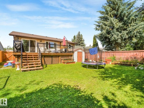Expansive green lawn with a multi-level wood deck and glass panel railing - 2035 49A Street, Edmonton, AB 