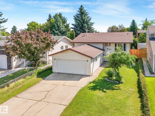 Exterior featuring a two-car garage, mature landscaping, fenced side yard, and a concrete driveway - 2035 49A Street, Edmonton, AB 