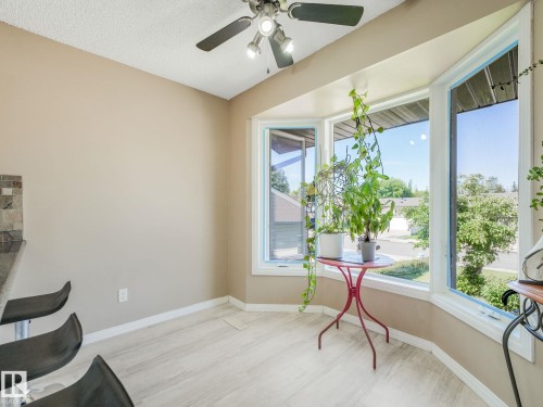 Bay window area with light wood-finish flooring, a ceiling fan with integrated lighting, and neutral wall paint - 2035 49A Street, Edmonton, AB 