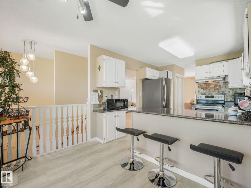 Kitchen featuring light wood-finish flooring, white cabinetry, and granite-look countertops - 2035 49A Street, Edmonton, AB 