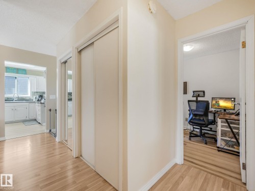 Hallway featuring light wood-finish flooring, white baseboards, and a built-in mirrored closet - 2035 49A Street, Edmonton, AB 