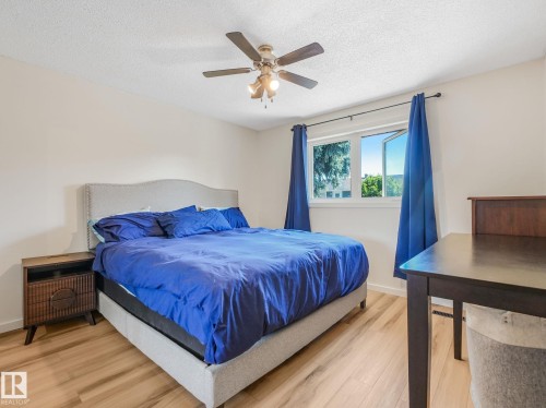 Bedroom featuring light wood-finish flooring, a ceiling fan with integrated lighting, and a window with a white frame - 2035 49A Street, Edmonton, AB 