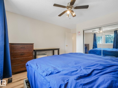 Bedroom featuring wood-finish flooring, a ceiling fan with integrated lighting, and a mirrored closet door - 2035 49A Street, Edmonton, AB 