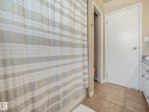 Bathroom featuring neutral-toned tile flooring and white vanity cabinetry with a light-toned countertop - 2035 49A Street, Edmonton, AB 