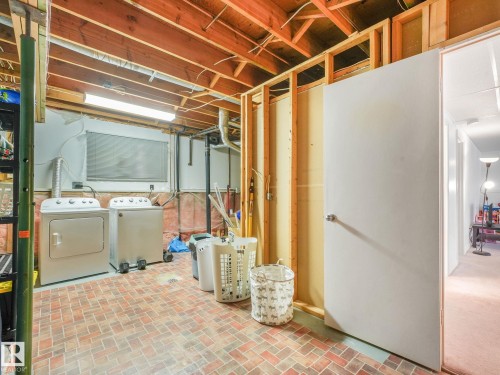 Utility space featuring brick-patterned flooring, exposed ceiling joists, and fluorescent lighting - 2035 49A Street, Edmonton, AB 