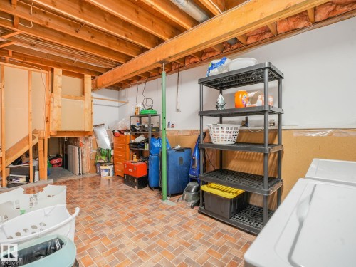 Unfinished basement featuring exposed wood ceiling joists and support beams, partial drywall, and terracotta-toned tile flooring - 2035 49A Street, Edmonton, AB 