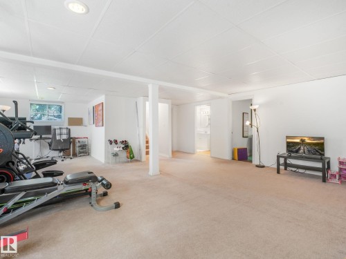 Open-concept lower level with light-toned carpet flooring and white acoustic panel ceiling - 2035 49A Street, Edmonton, AB 