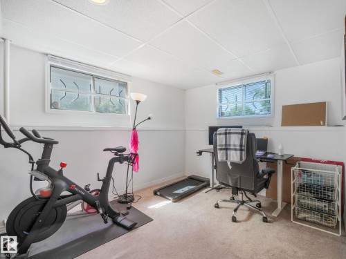 Carpeted room with drop ceiling, two distinct windows, and light-toned walls featuring a chair rail - 2035 49A Street, Edmonton, AB 