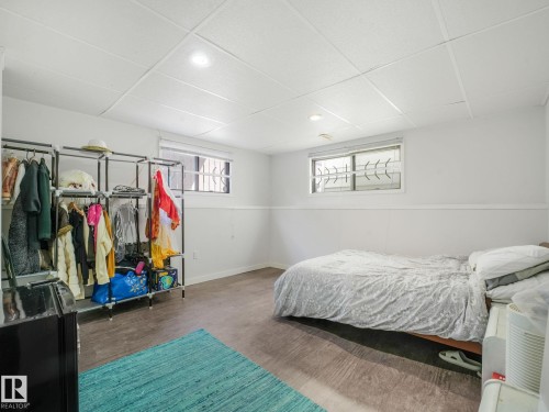 Spacious room featuring wood-finish flooring, white walls with wainscoting, and a white acoustic tile ceiling with recessed lighting - 2035 49A Street, Edmonton, AB 