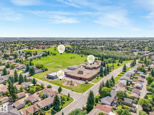 Aerial perspective showcasing a residential neighborhood with a large institutional building featuring brown roofing and an adjacent playground - 2035 49A Street, Edmonton, AB 